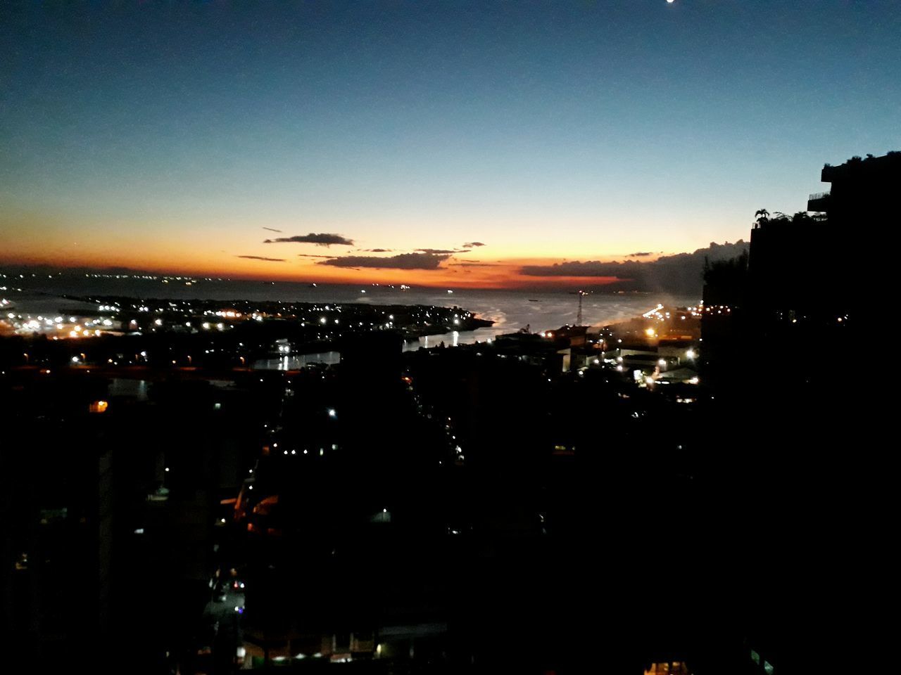 HIGH ANGLE VIEW OF ILLUMINATED CITY AT SUNSET