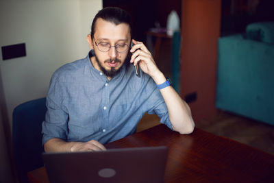 Young man using mobile phone while sitting at home