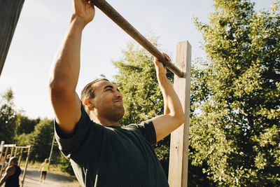 Male athlete exercising on monkey bar in park