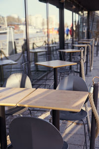 Empty chairs and tables at sidewalk cafe