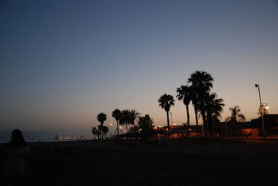 Silhouette palm trees on beach against clear sky at sunset