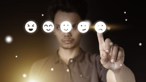 Portrait of young man standing against black background