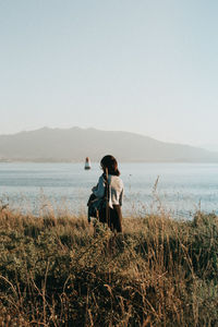 Rear view of woman walking on field against sky