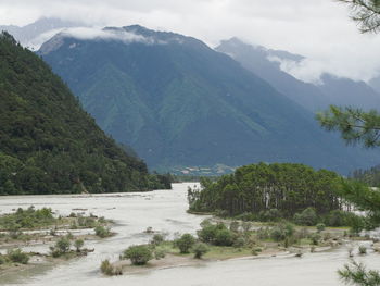 Scenic view of mountains by parlung zangbo river against cloudy sky