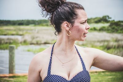 Woman wearing tank top looking away while standing outdoors