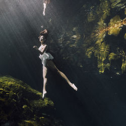 Woman underwater by rock formation 