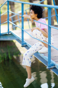 Side view of young woman standing against railing