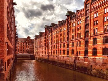 Canal amidst buildings in city against sky