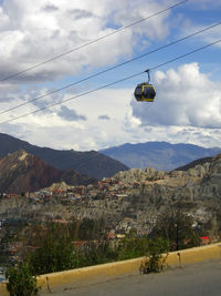 Overhead cable car over mountains against sky