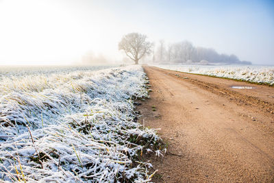 Scenic view of snowy field against sky during winter