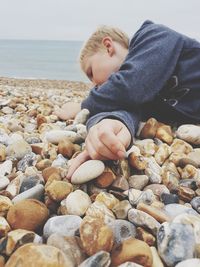 Boy lying down on pebbles at beach