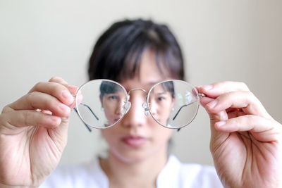 Close-up portrait of young woman holding eyeglasses