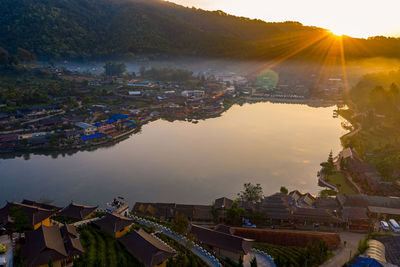 High angle view of river by townscape against sky at sunset
