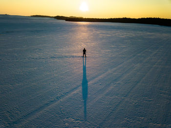 High angle view of silhouette person on shore against sky during sunset