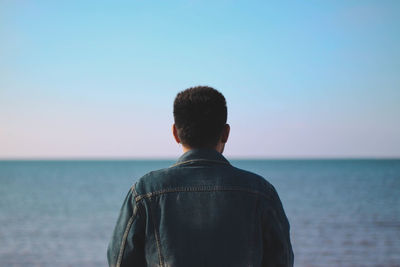 Rear view of man looking at sea against sky