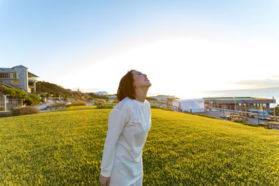 Woman standing on grass against clear sky