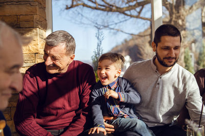 Grandparents looking at son talking to grandson at home