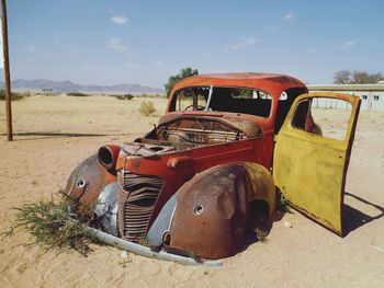 Abandoned car on field against sky