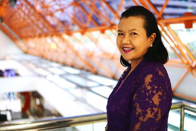 Portrait of smiling mature woman standing by railing