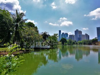 Scenic view of lake by trees and buildings against sky