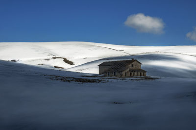 House on snow covered landscape against clear sky