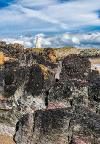 People on rock by building against sky