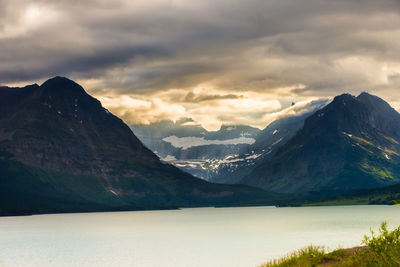 Scenic view of lake and mountains against cloudy sky