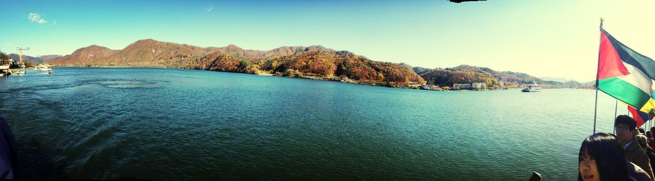 sea, mountain, water, nautical vessel, scenics, tranquil scene, tranquility, transportation, beauty in nature, sky, nature, boat, mode of transport, blue, mountain range, sunlight, panoramic, clear sky, travel, incidental people