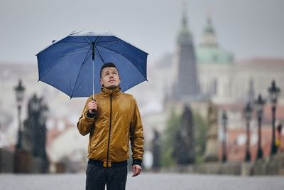 Man with umbrella standing in city during rainy season