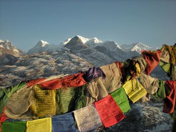 Prayer flags hanging over mountain against sky during winter