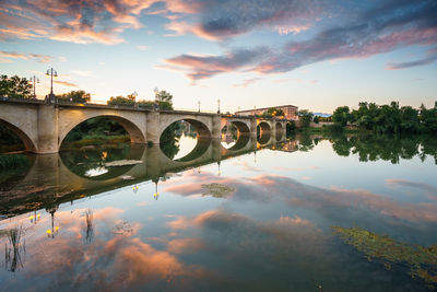 Bridge over river against sky during sunset