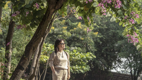 Woman standing by tree against plants