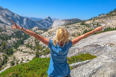 Woman with arms outstretched against mountain range