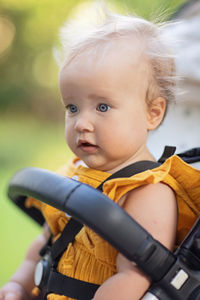 Portrait of cute caucasian baby girl in carriage in park 