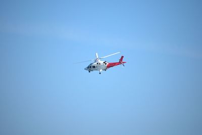 Low angle view of helicopter flying against clear blue sky