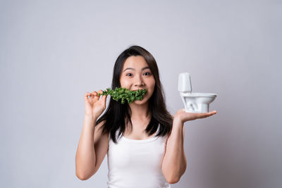 Portrait of a smiling young woman standing against white background