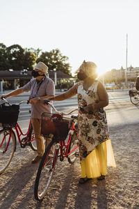 Senior couple with bicycle standing at roadside on sunny day