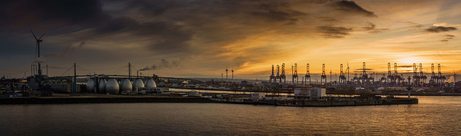 Sailboats on pier at harbor against sky during sunset