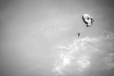 Low angle view of man parasailing against sky