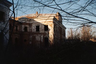 Abandoned house against bare tree