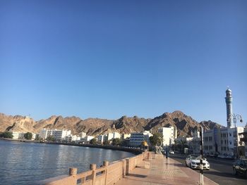 View of city at waterfront against blue sky