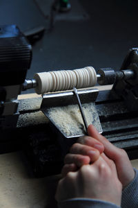 High angle view of cropped hands cutting wood