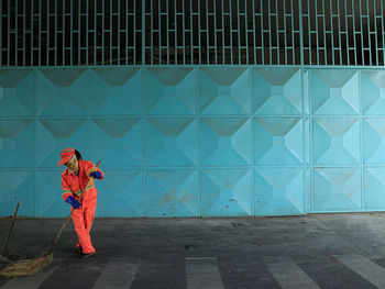 Full length of man holding umbrella standing against wall