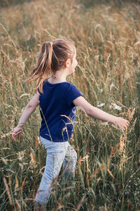 Girl walking amidst grassy field