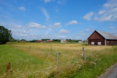 Scenic view of field by houses against sky