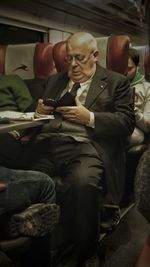Man holding smart phone while sitting in bus