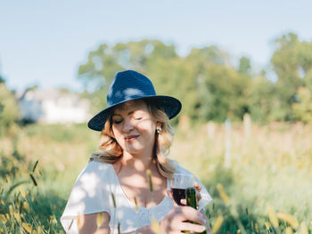 Portrait of smiling young woman wearing hat on field