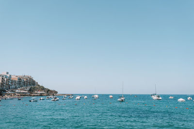 Sailboats in sea against clear sky