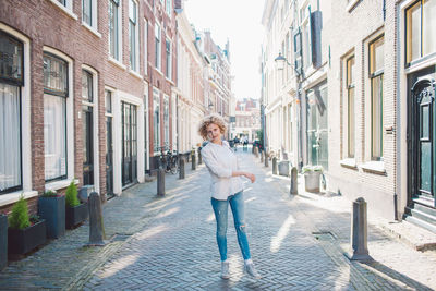 Portrait of woman standing on street amidst buildings in city