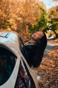 Woman wearing sunglasses while sitting on car